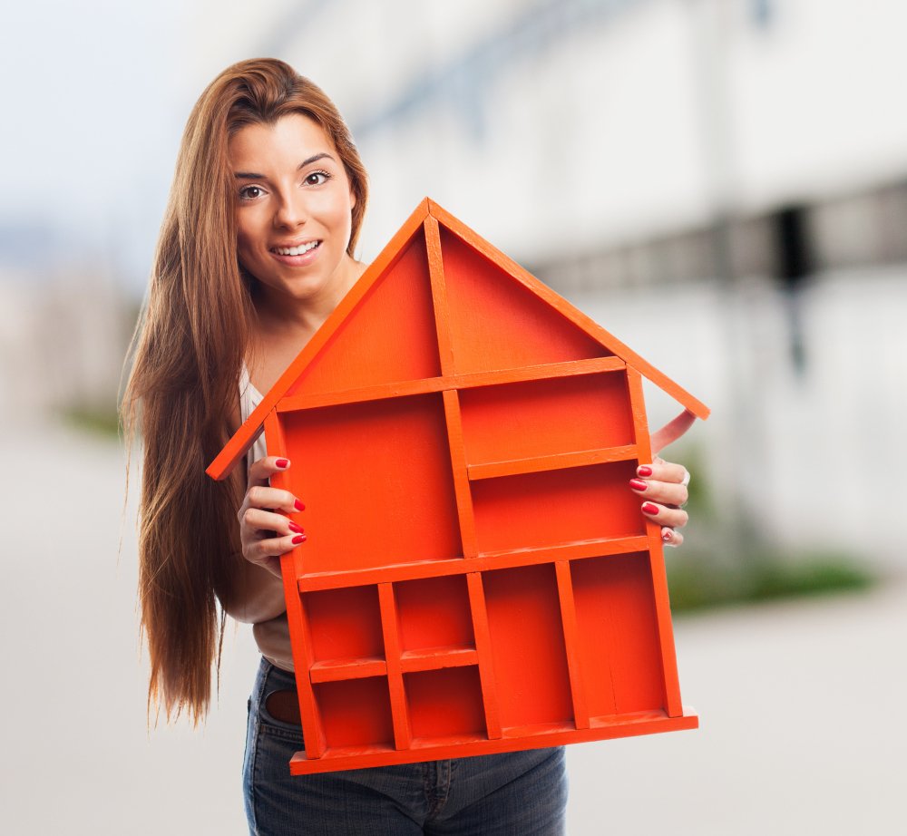 A young girl holding a wooden small home in hands.